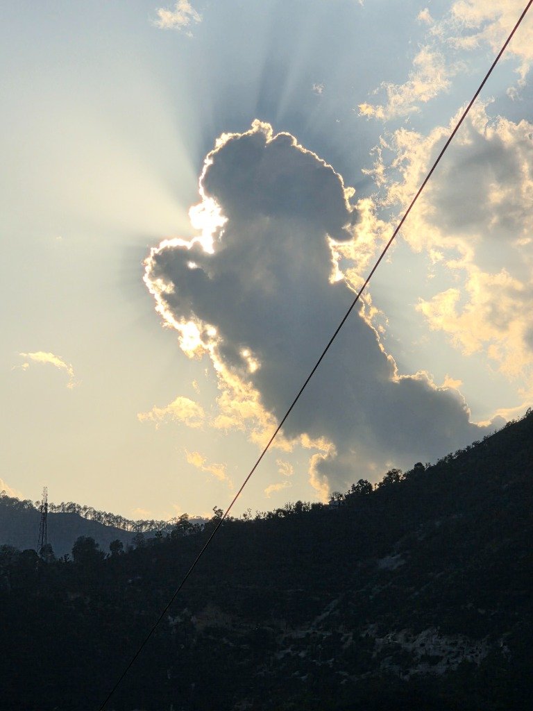 A majestic cloud formation back-lit by divine sun rays over the ridge