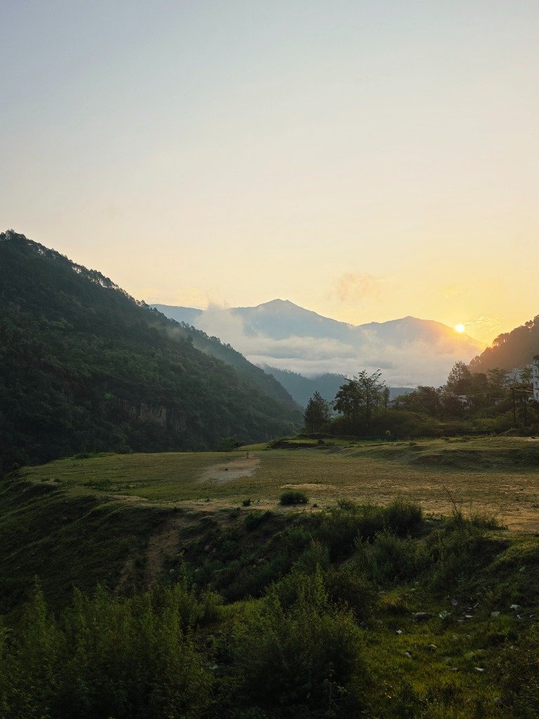 Misty morning meadow surrounded by green mountain slopes